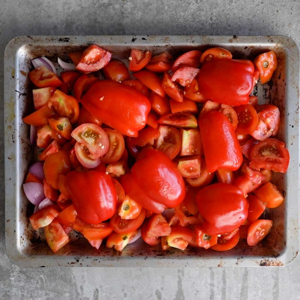 Tomatoes, red peppers and onions on a baking tray