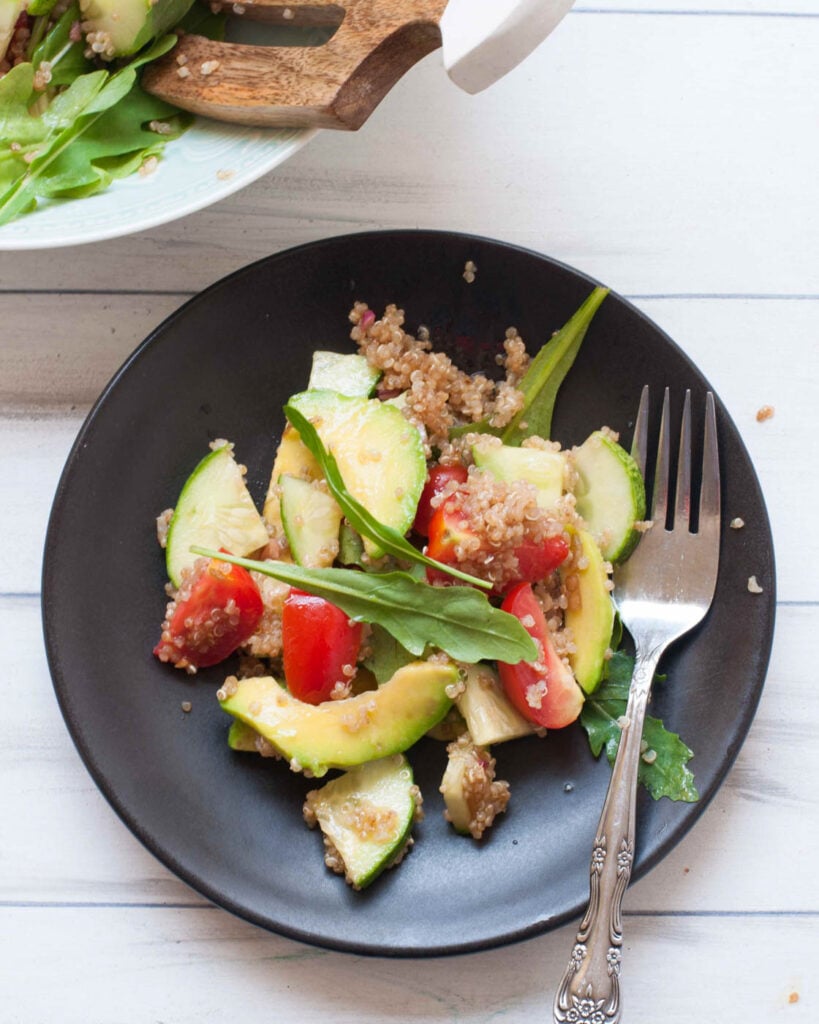 quinoa salad with balsamic dressing on a black plate with an ornate fork