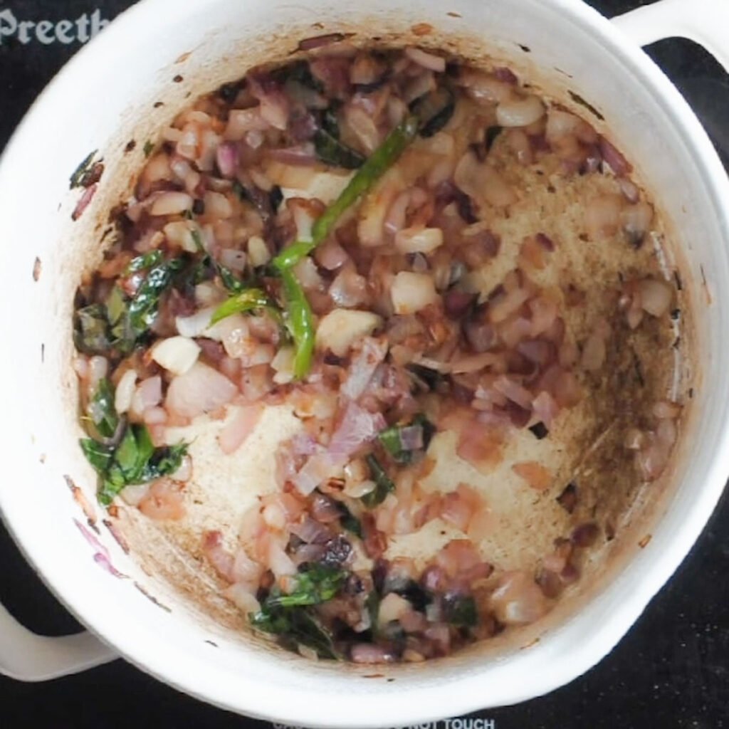 Onions being browned inside a white pot