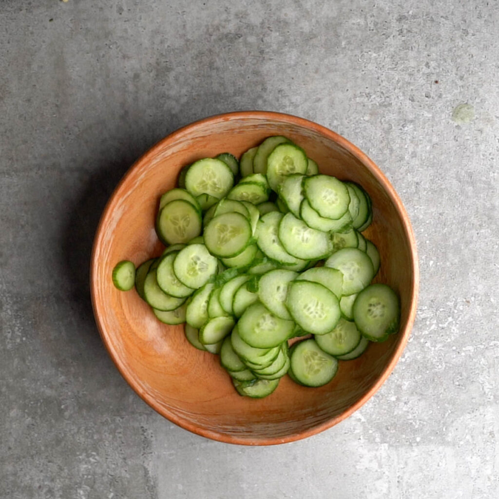 Cucumber cut into thin slices in a wooden bowl