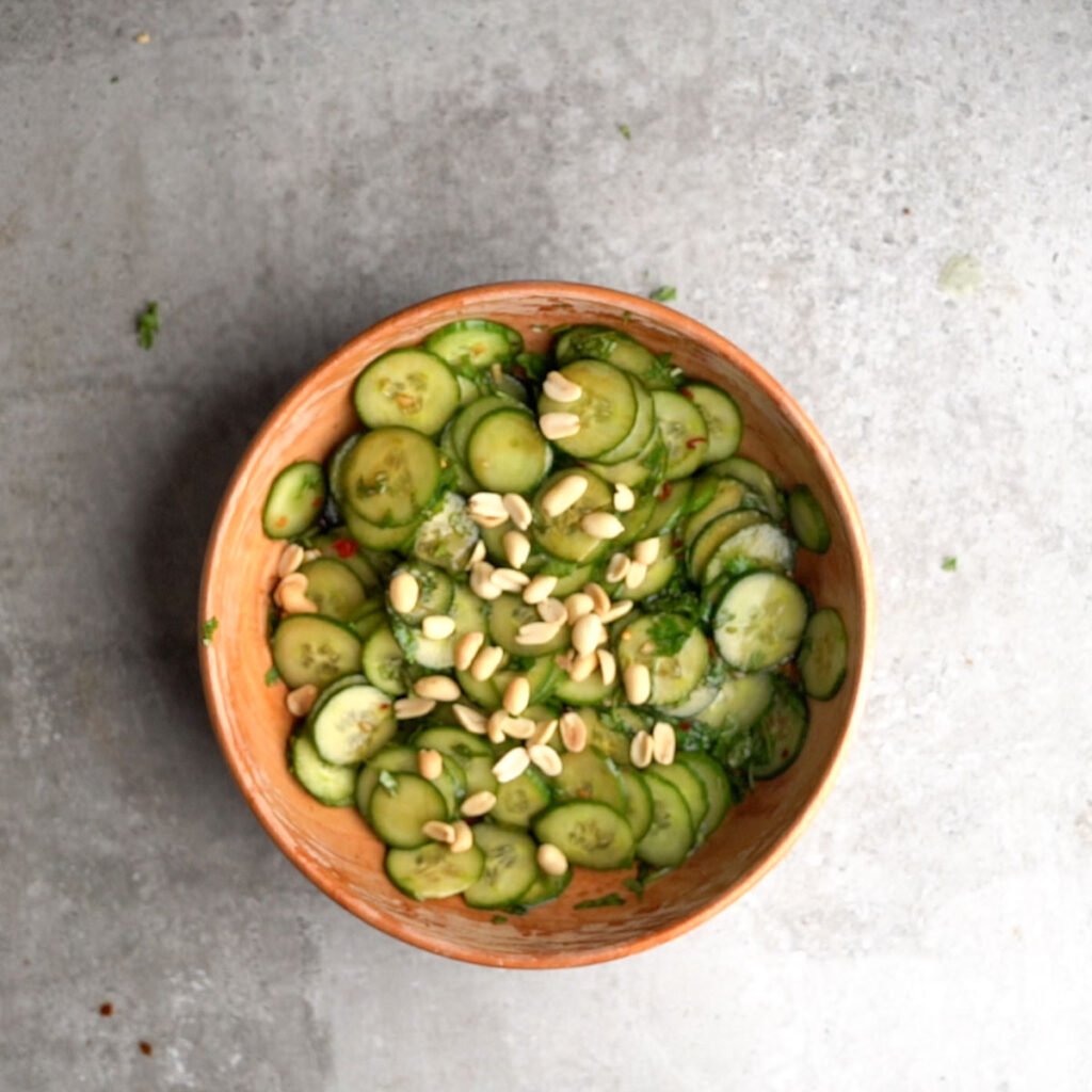 Spicy Asian Cucumber salad mixed in a wooden bowl , garnished with peanuts