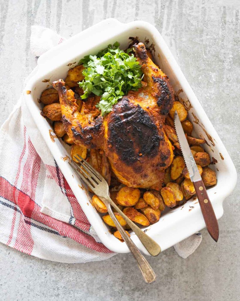 Indian style Roasted Chicken in a white baking dish with baby potatoes
