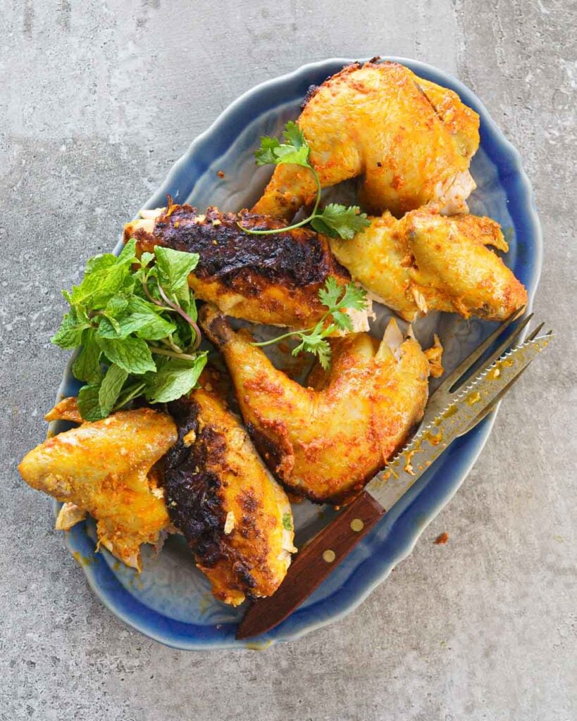 Cut roast chicken on a blue plate with a fork and knife