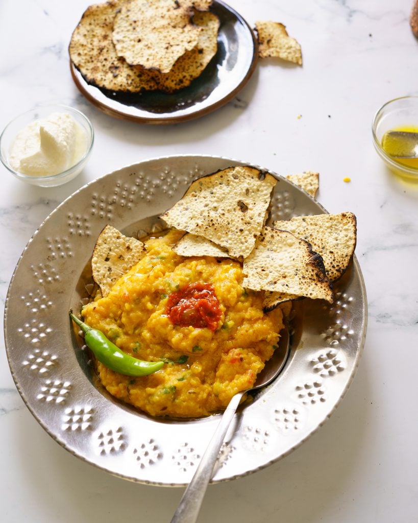 Instant Pot Moong Dal Khichdi(Kichdi /kitchari) in a steel plate with pickle, papapd, onions and a chili