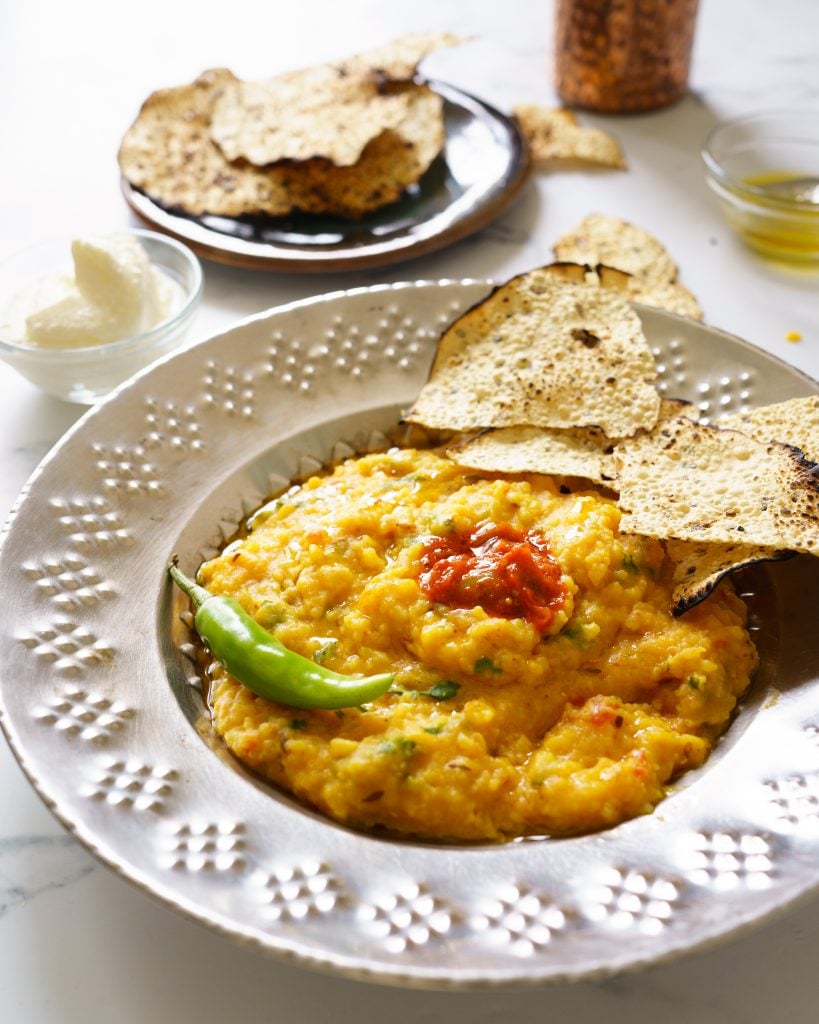 Instant Pot Moong Dal Khichdi(Kichdi /kitchari) in a steel plate with pickle, papapd, onions and a chili