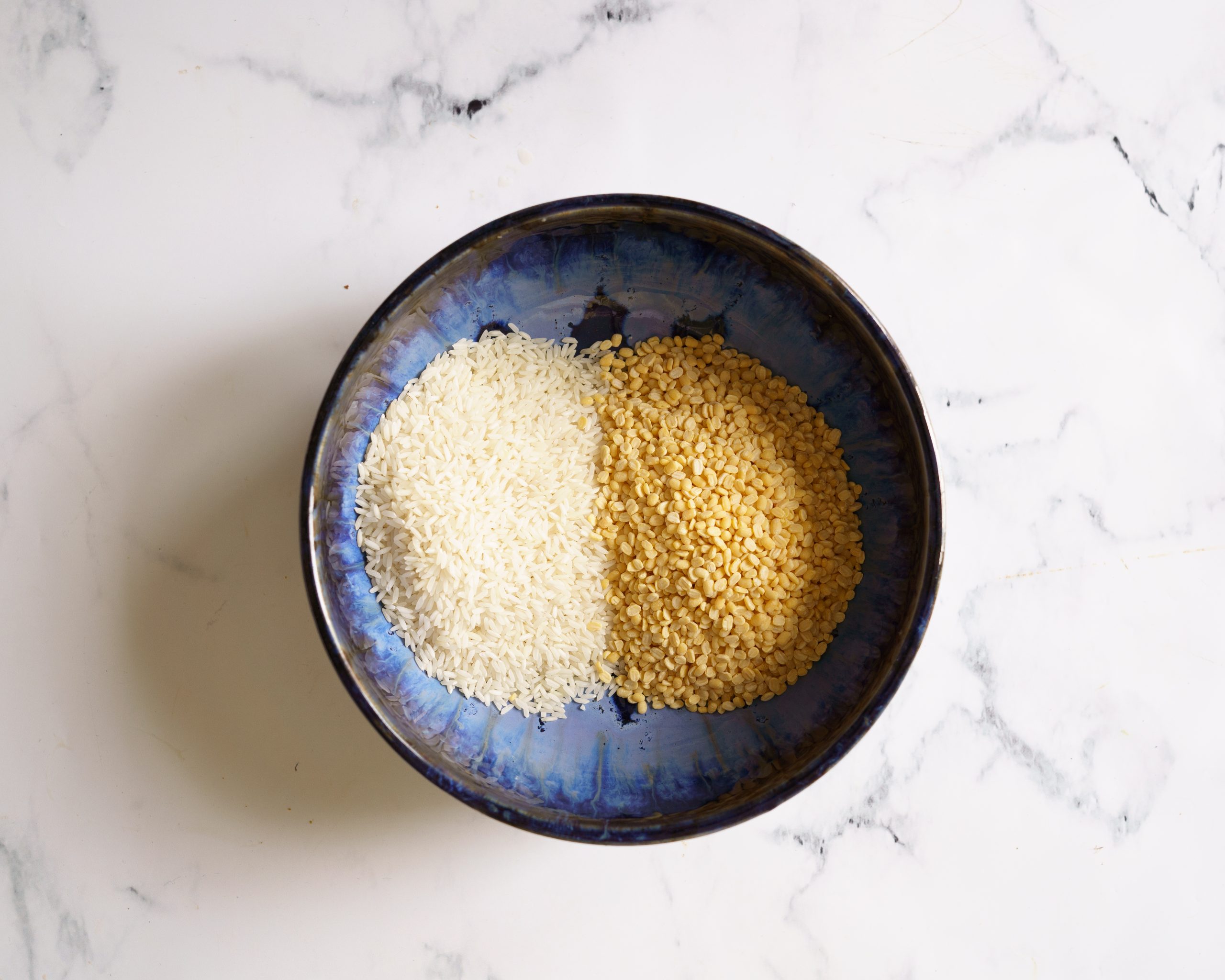 washing rice and dal in a blue bowl to make khichdi
