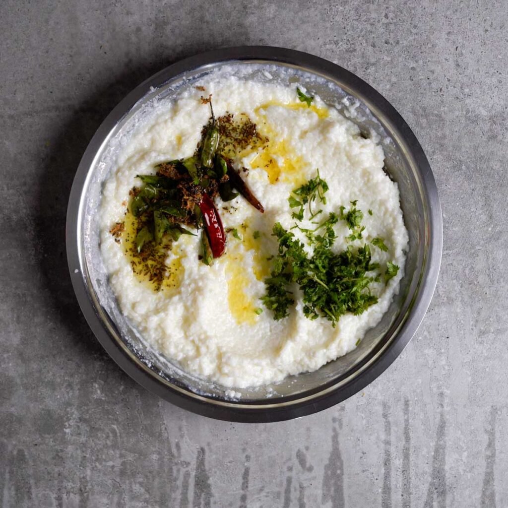 Curd rice with tempering of curry leaves, chilies and mustard seeds and chopped coriander on top of it