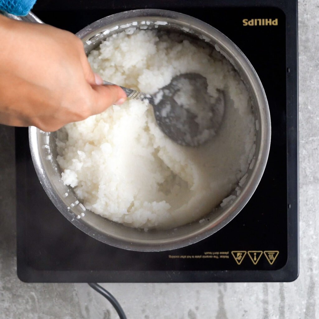 Mashing the just cooked soft rice to make curd rice