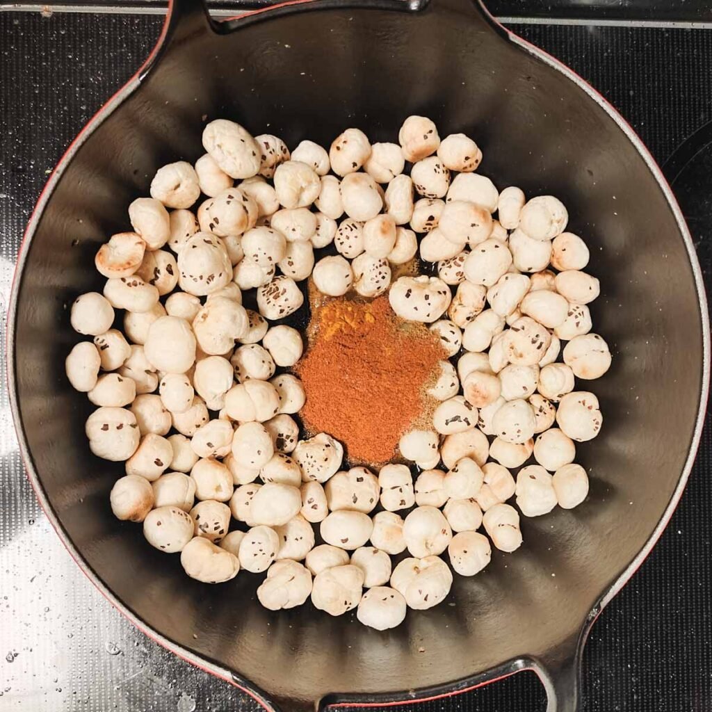 makhana inside a black wok with spices in the middle
