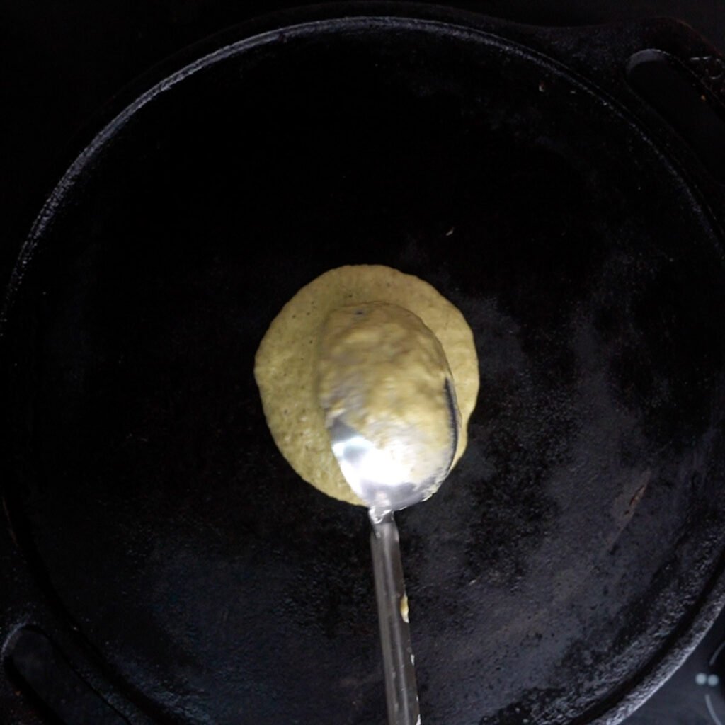 Making Pesarattu dosa starting with a dollop of dosa batter on a hot tawa