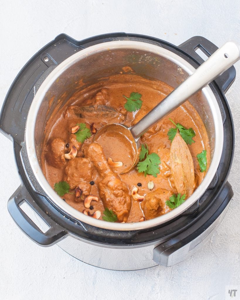 chicken korma in an instant pot with coriander leaves and cashews as garnish