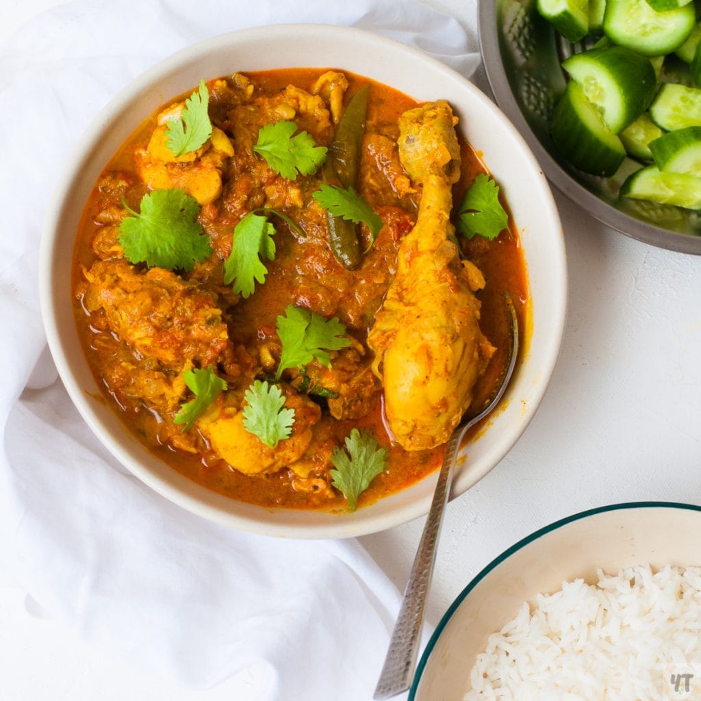 Instant Pot Indian Chicken Curry in a white bowl with rice and cucumber salad