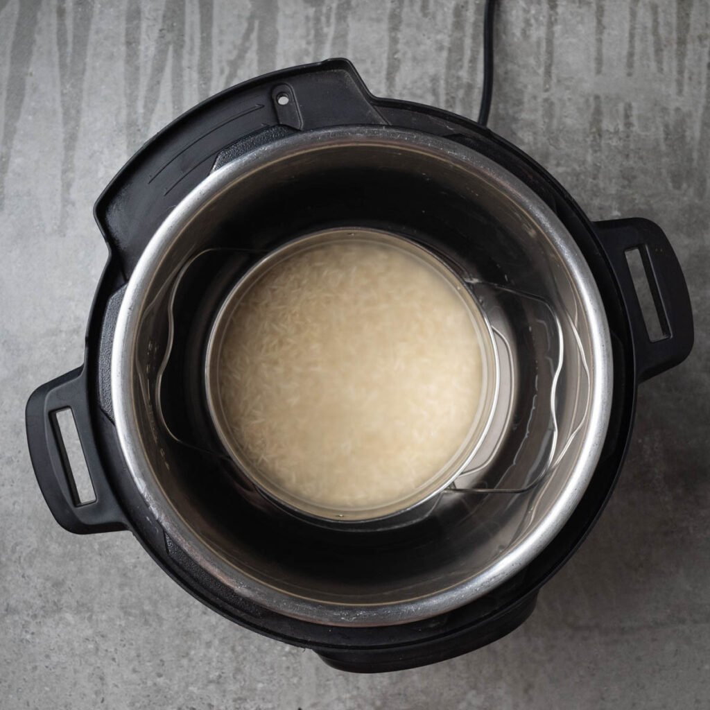 Pot in pot method of cooking in the instant pot.A trivet with a bowl of rice and water inside the inner steel insert