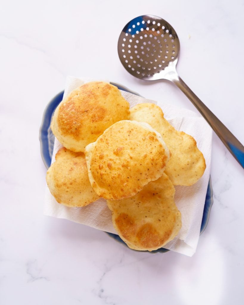 6 Golden brown Bhature on a blue long platter lined with kitchen towel