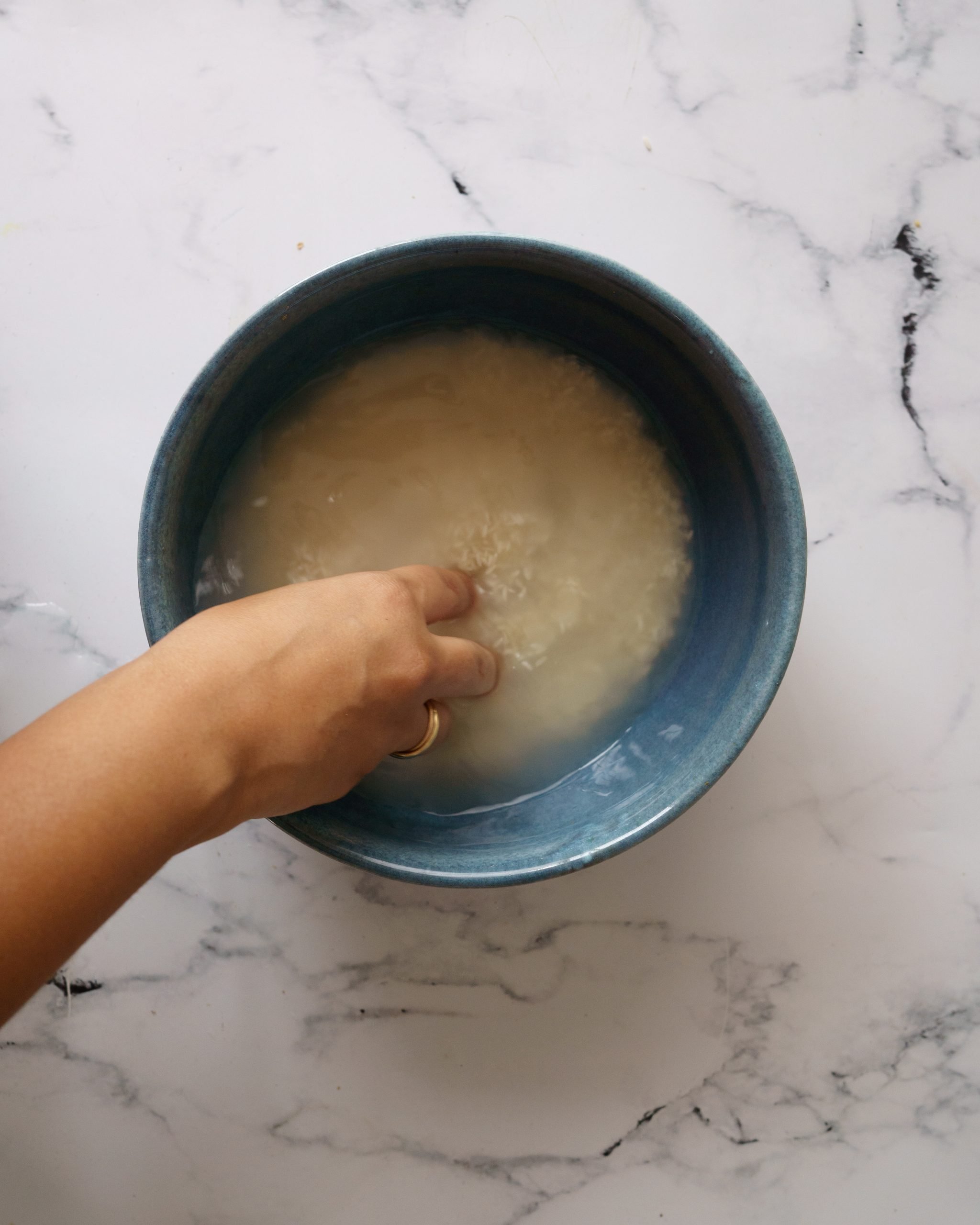 washing the rice in blue bowl