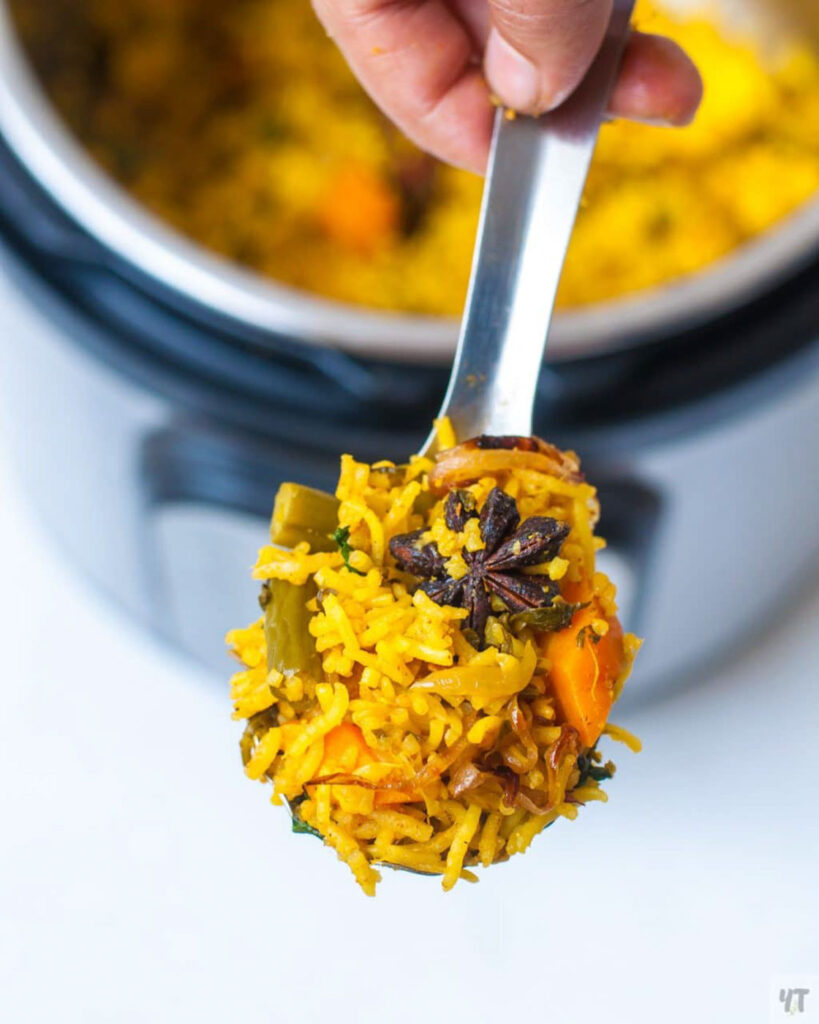 A ladle full of vegetable biryani cooked in the instant pot , along with a piece of star anise