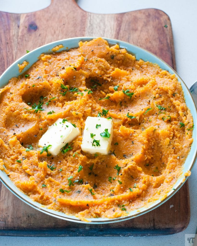Mashed Sweet Potatoes in a green bowl with butter and parsley