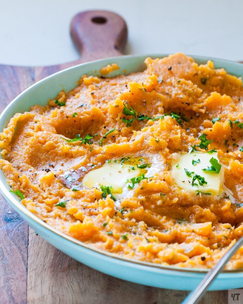 Instant Pot Mashed Sweet Potatoes in a green bowl with butter and parsley