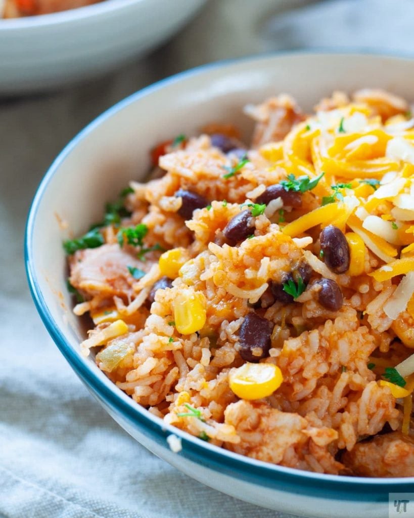 Instant Pot Burrito Bowl- Mexican Rice with Chicken & Beans in a white bowl with a green rim