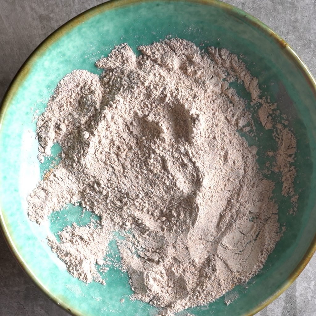 mixing dry ingredients in a shallow green bowl to make Ragi cookies