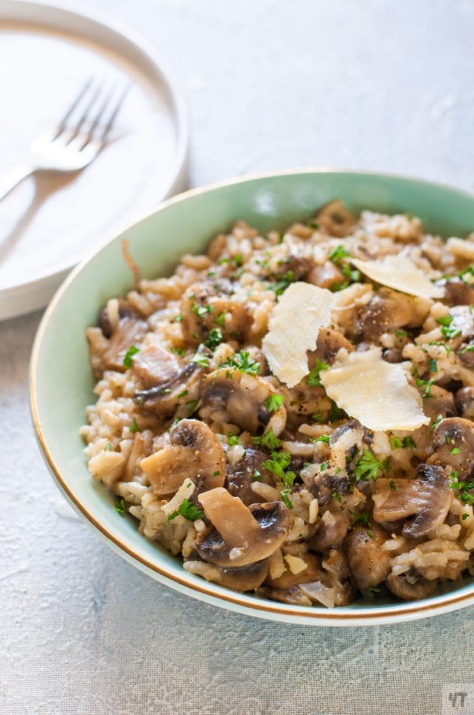 Mushroom Risotto in a green bowl with parsley and parmesan cheese