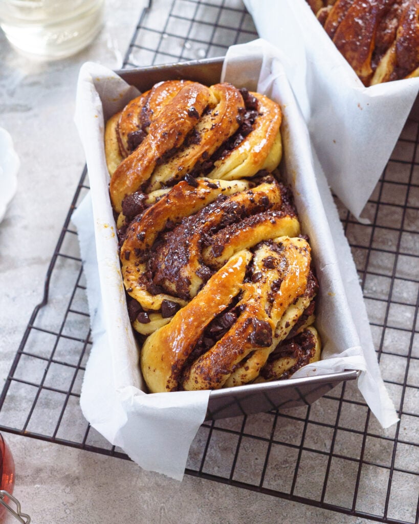 Chocolate Babka loaf in a loaf pan, lined with parchment paper, kept on top of a cooling rack