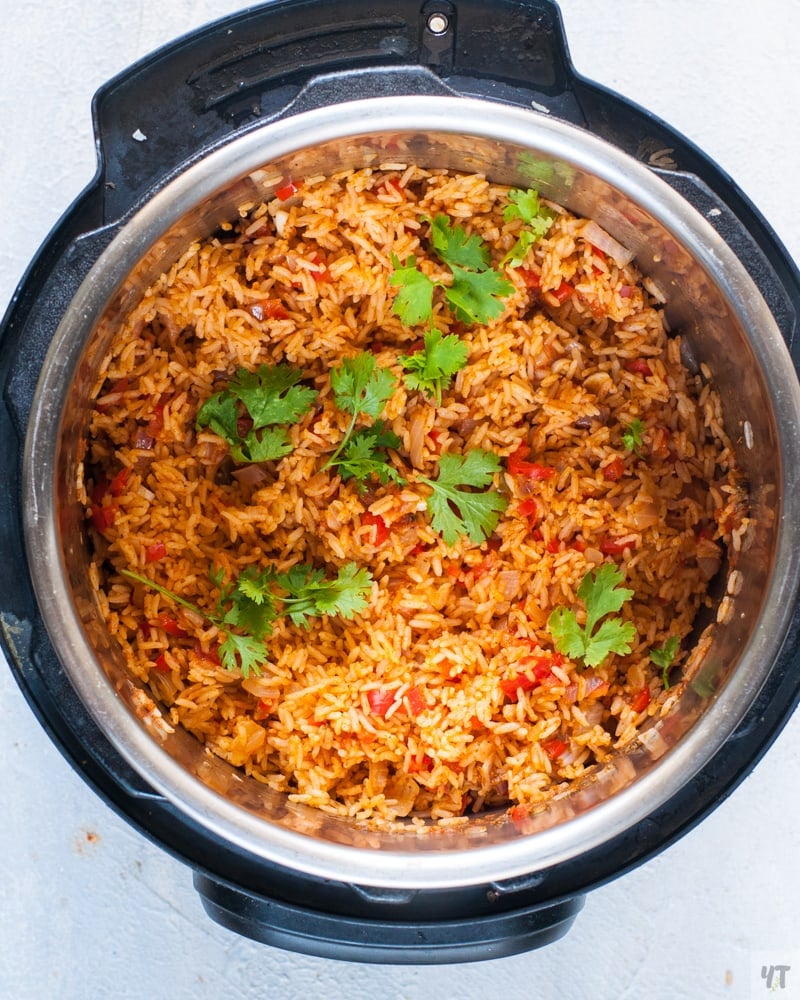 Cooked Spanish rice in the instant pot, garnished with sprigs of cilantro