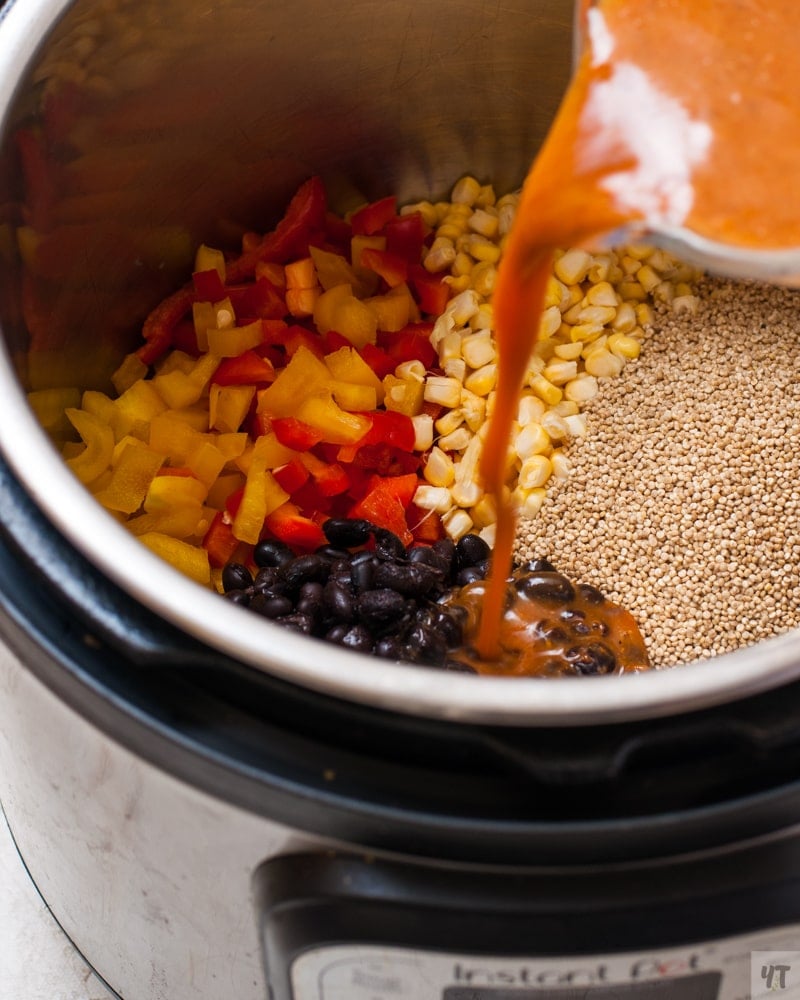 Quinoa, beans, bell peppers and enchilada sauce with water in the instant pot to make maexican quinoa