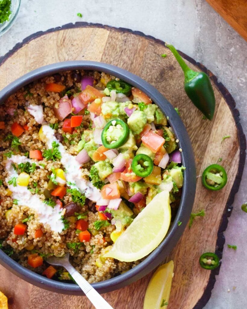 Instant Pot Mexican Quinoa Bowl with a lemon wedge, avocado salad in a black bowl