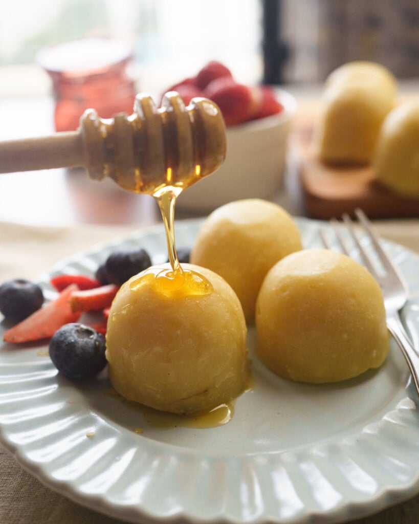 Pancake bites made in the instant pot on a blue plate with a fork and with a drizzle of honey.