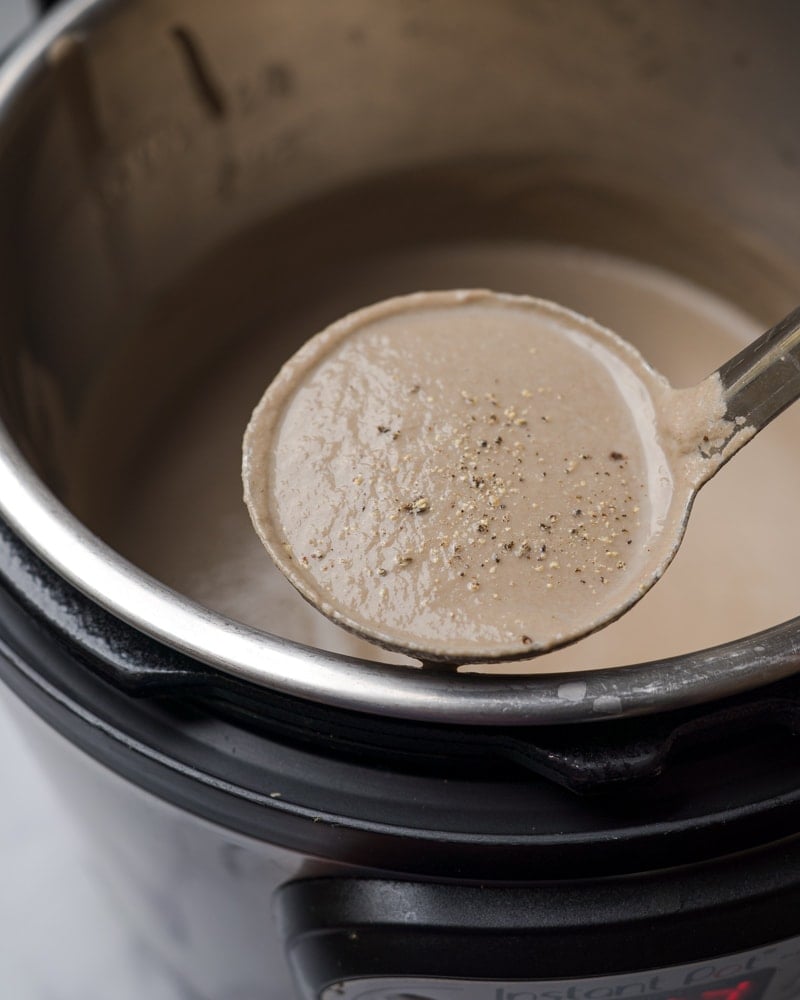 Instant Pot Mushroom Soup in a laddle with pepper flakes