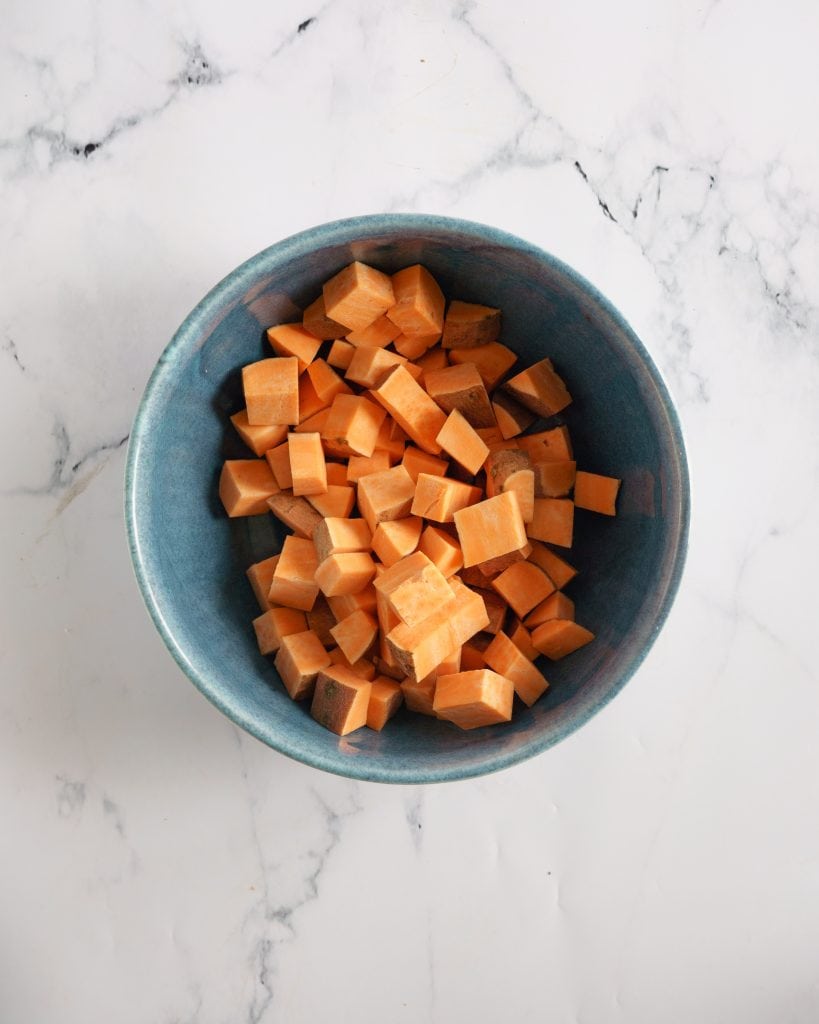 Sweet potato cubes in a blue bowl with white background