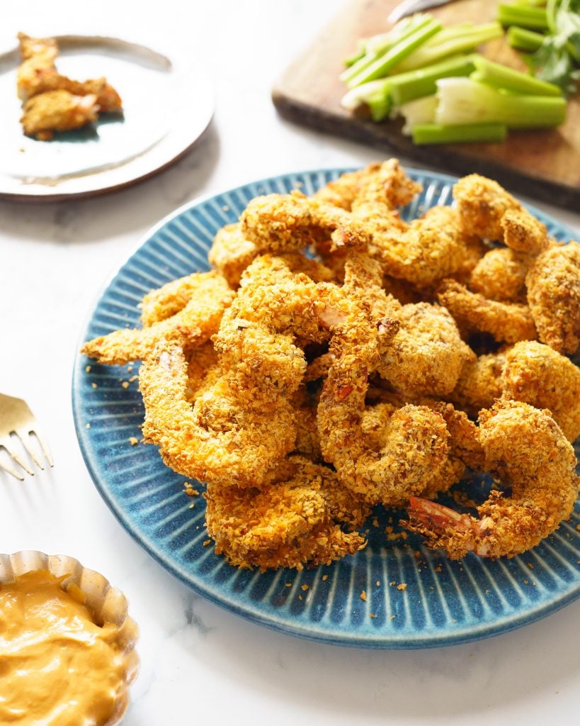 Popcorn Shrimp in a blue plate, with celery sticks in the background