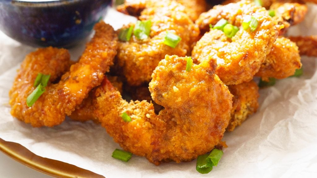 Air Fryer Buffalo Shrimp on a plate with parchment paper, celery and mayonnaise