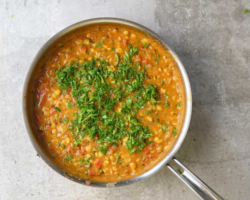 cooked Chana Dal inside a steel flat pan , garnished with coriander.