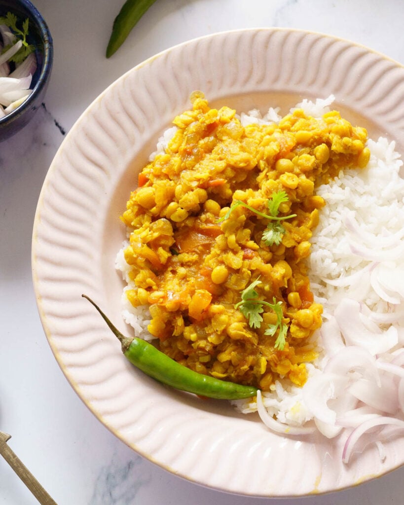 Chana Dal served on top of rice, in a pink bowl along with onions, chili and coriander