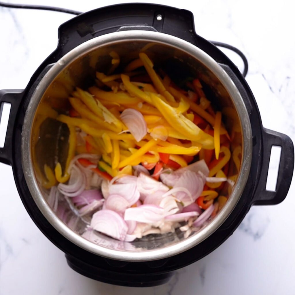 Sliced chicken in the instant pot along with bell peppers and onions