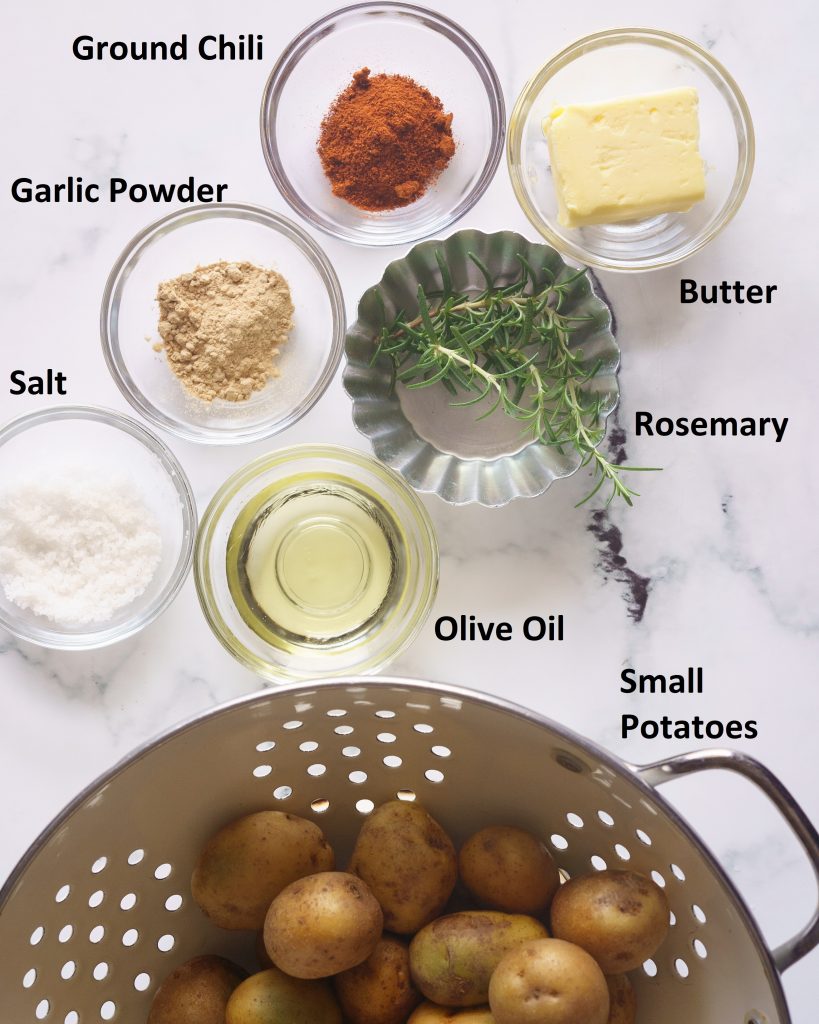Ingredients to make Smashed Rosemary Garlic potatoes -from the top- butter, ground chili, garlic powder, salt, olive oil, Rosemary and small potatoes, 