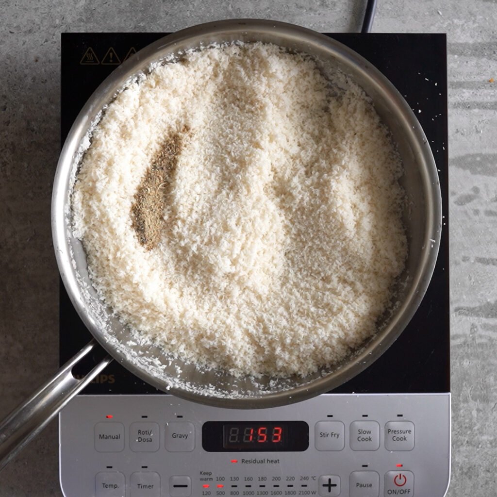 Adding cardamom to the Toasted coconut to make Coconut Ladoo