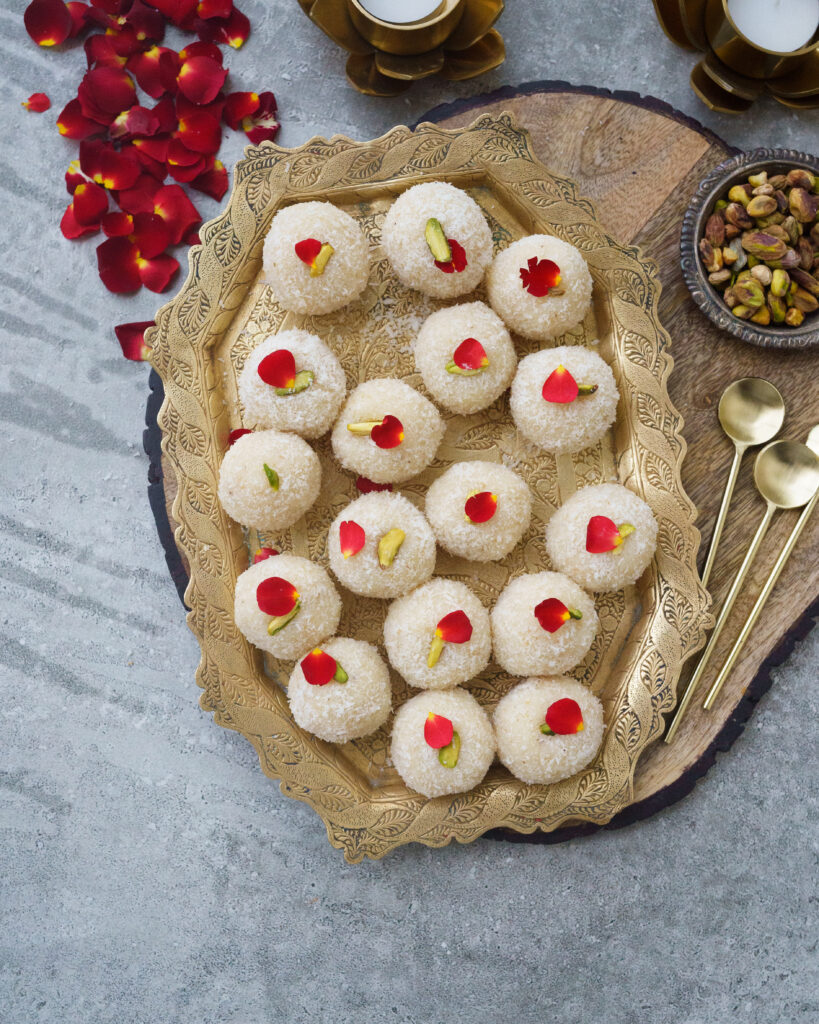 Coconut Ladoos made with Condensed milk,Dried coconut and cardamom on a golden plate, decorated with pistachios and rose petals