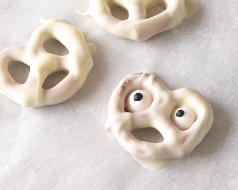 White chocolate covered ghost pretzel on a parchment paper 