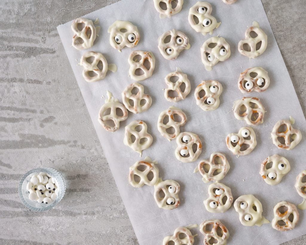 White chocolate covered ghost pretzels on a parchment paper