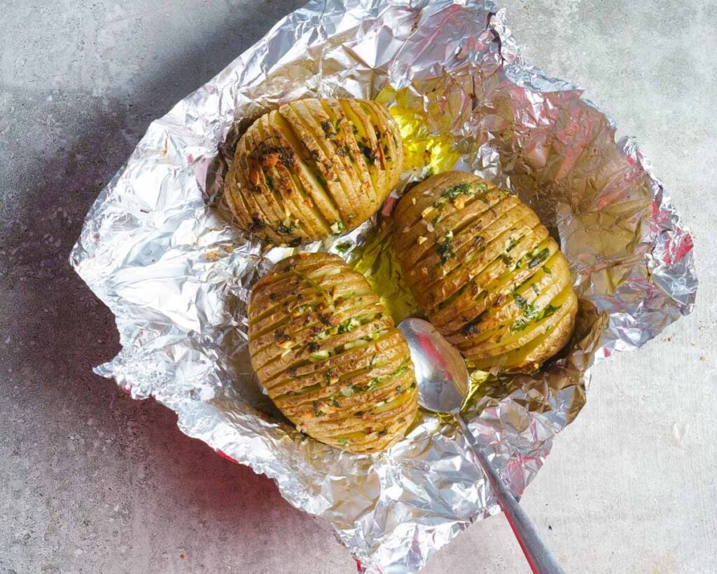 Cooked Browned Hasselback Potatoes on a foil  after being cooked.