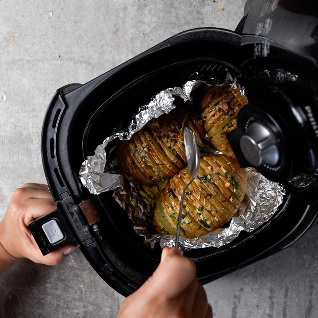 Cooked Browned Hasselback Potatoes on a foil inside the air fryer basket after being cooked.