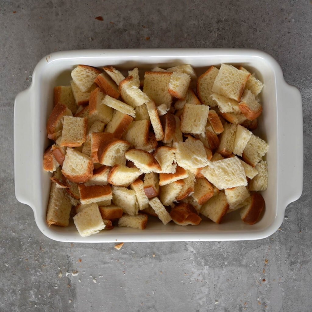 The bread cubes in a white baking dish 