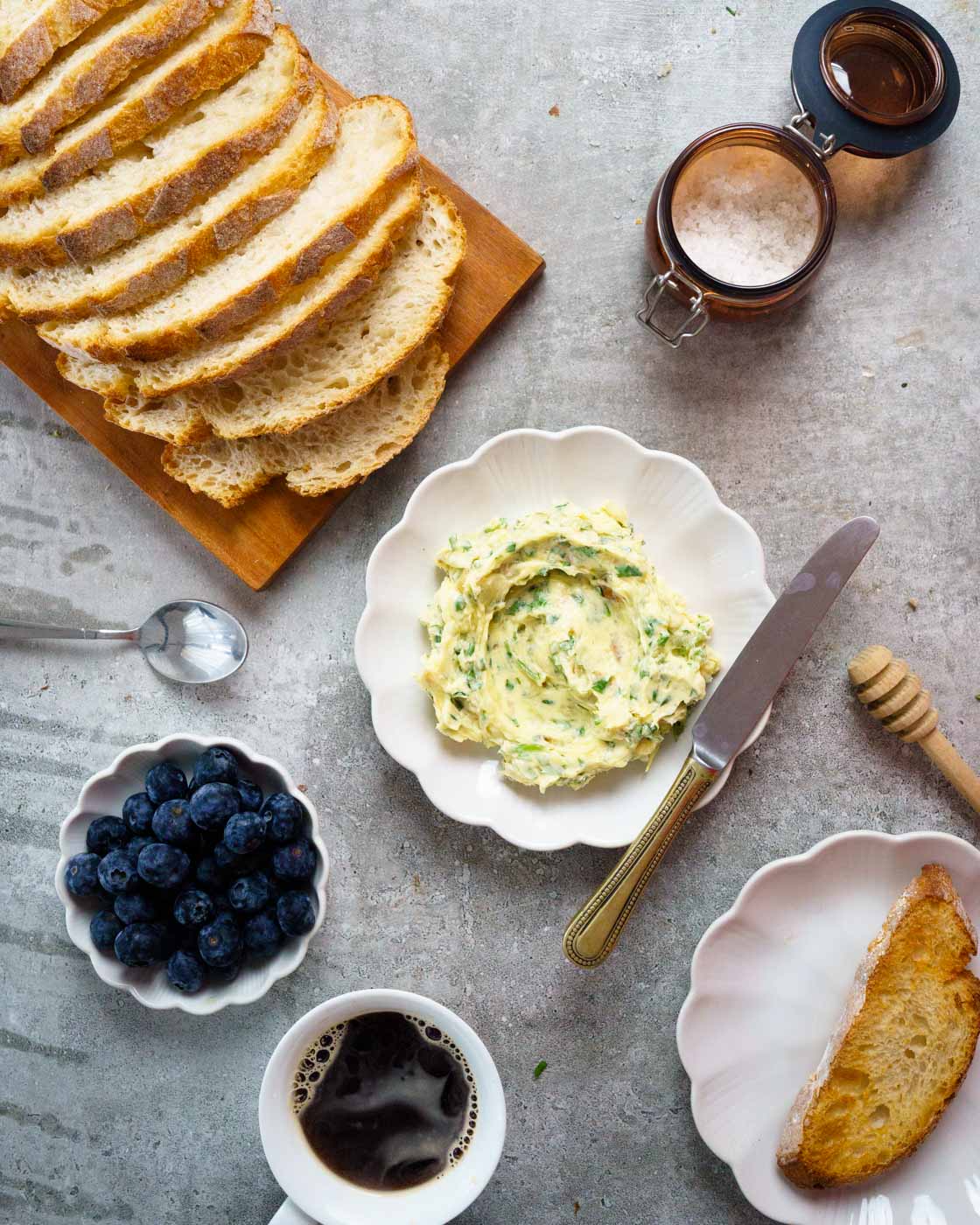 Breakfast spread on the table with sour dough bread, coffee, blueberries ,roasted garlic compound butter and a cup of coffee