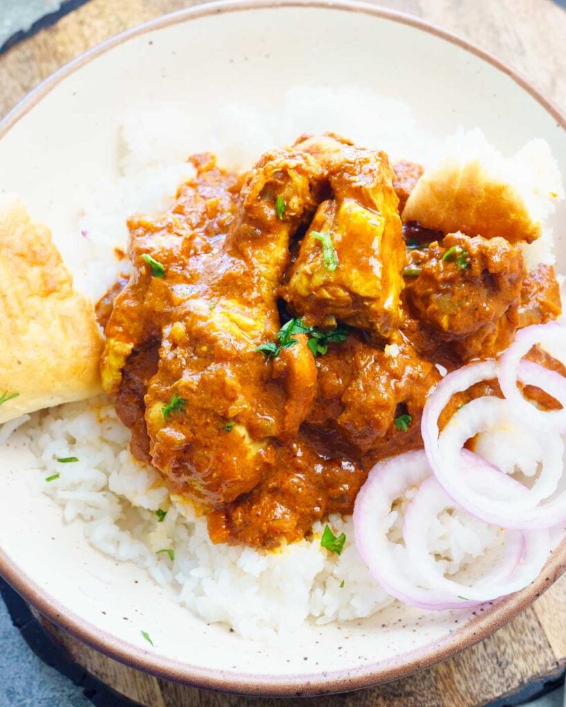 chicken vindaloo on top of rice with onions and bread