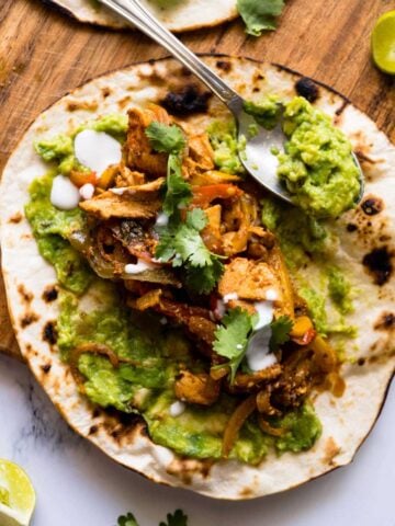 chicken fajitas on top of a toasted tortilla with smashed avocado