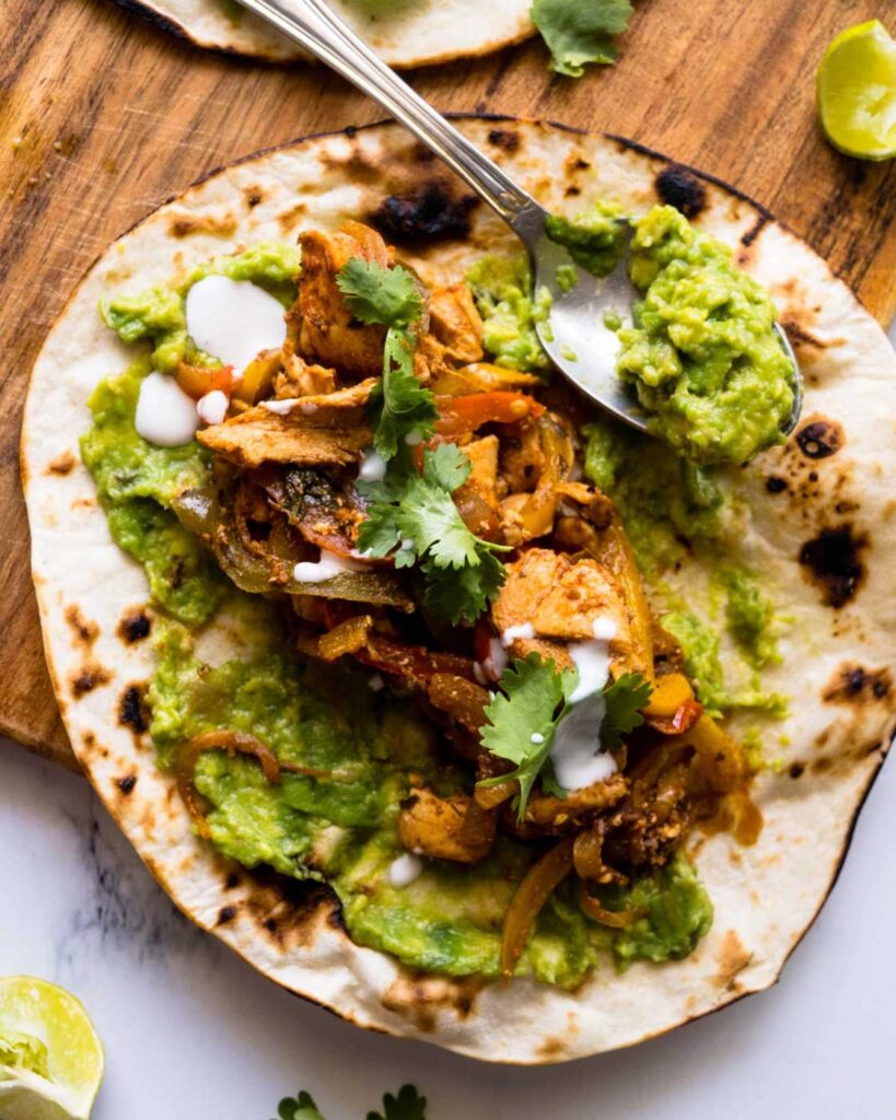 chicken fajitas on top of a toasted tortilla with smashed avocado