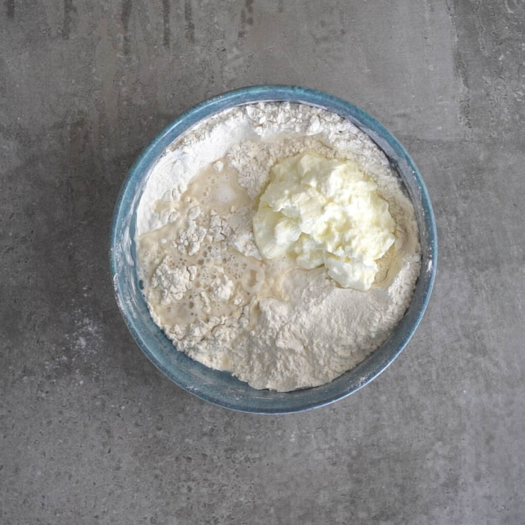 flour, yeast,baking powder, baking soda ,yogurt and water in a blue bowl
